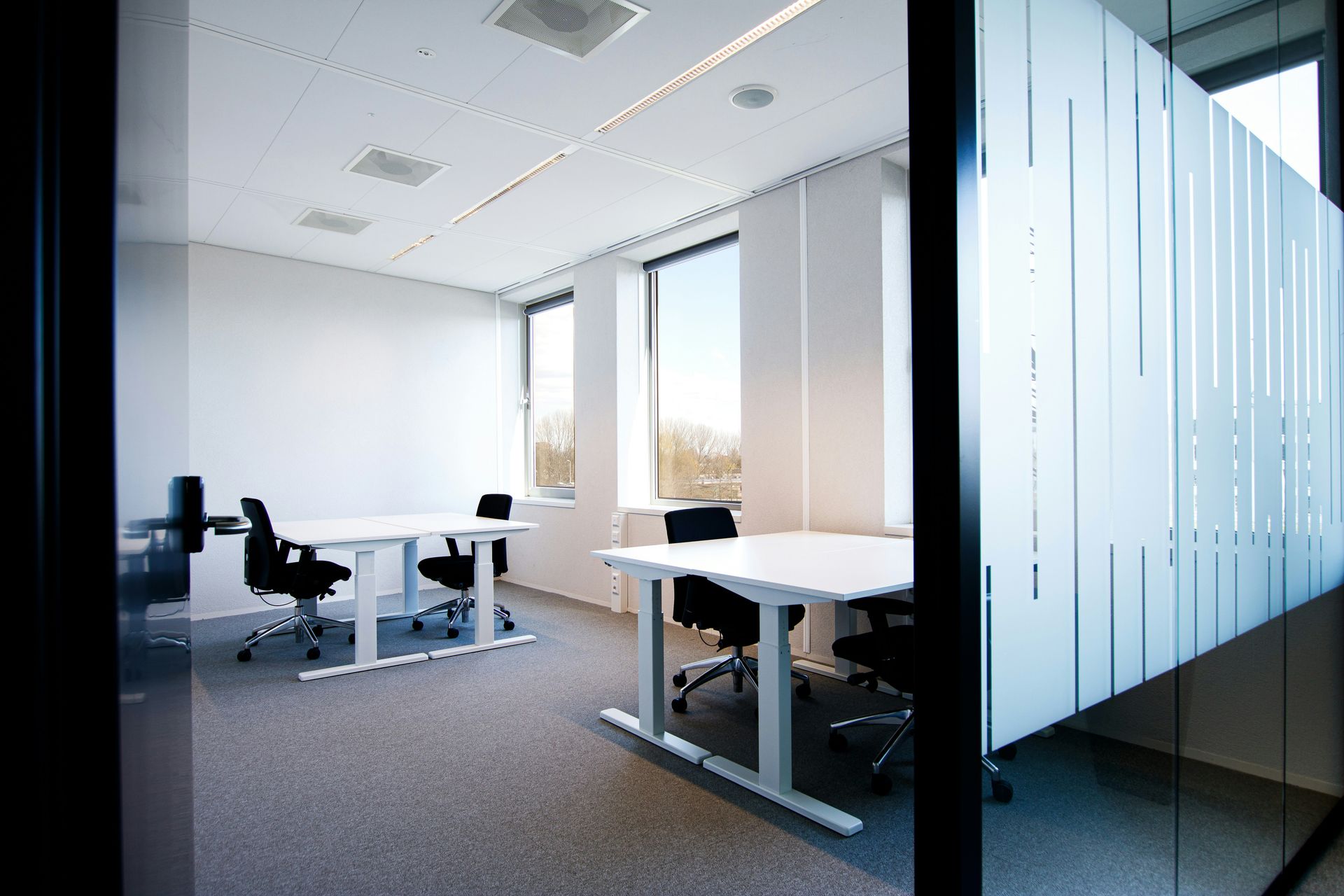 an office with a white table and black chairs